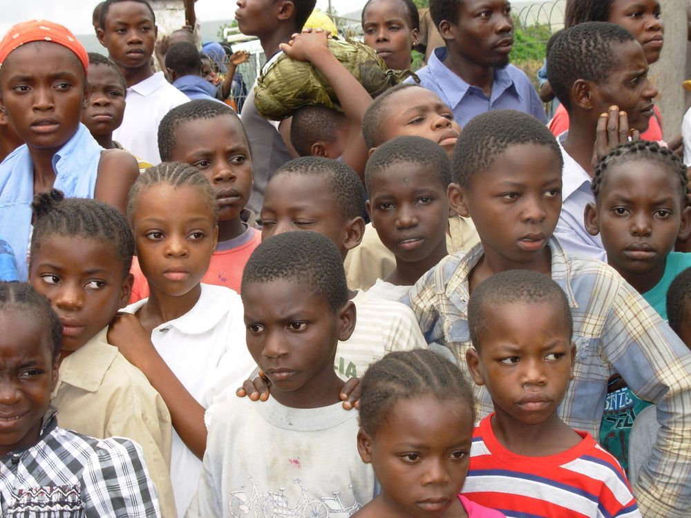 Eine dicht gedrängte Gruppe von Kindern steht im Freien beisammen und schaut in die Kamera.