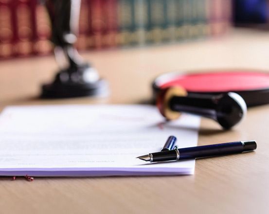 Un bolígrafo está sobre una hoja de papel sobre una mesa.