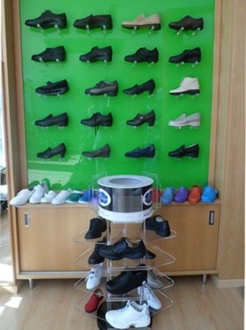 Pared expositora de zapatos con filas de zapatos, un soporte giratorio de zapatos al frente y un armario debajo.
