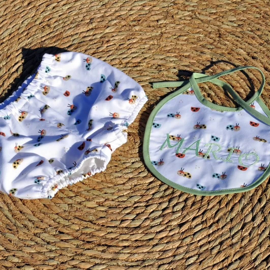 Un babero y un pañal de bebé se encuentran sobre una estera de mimbre.