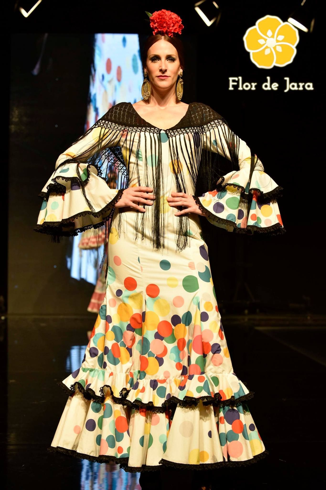 Una mujer camina por una pasarela con un vestido de lunares colorido.