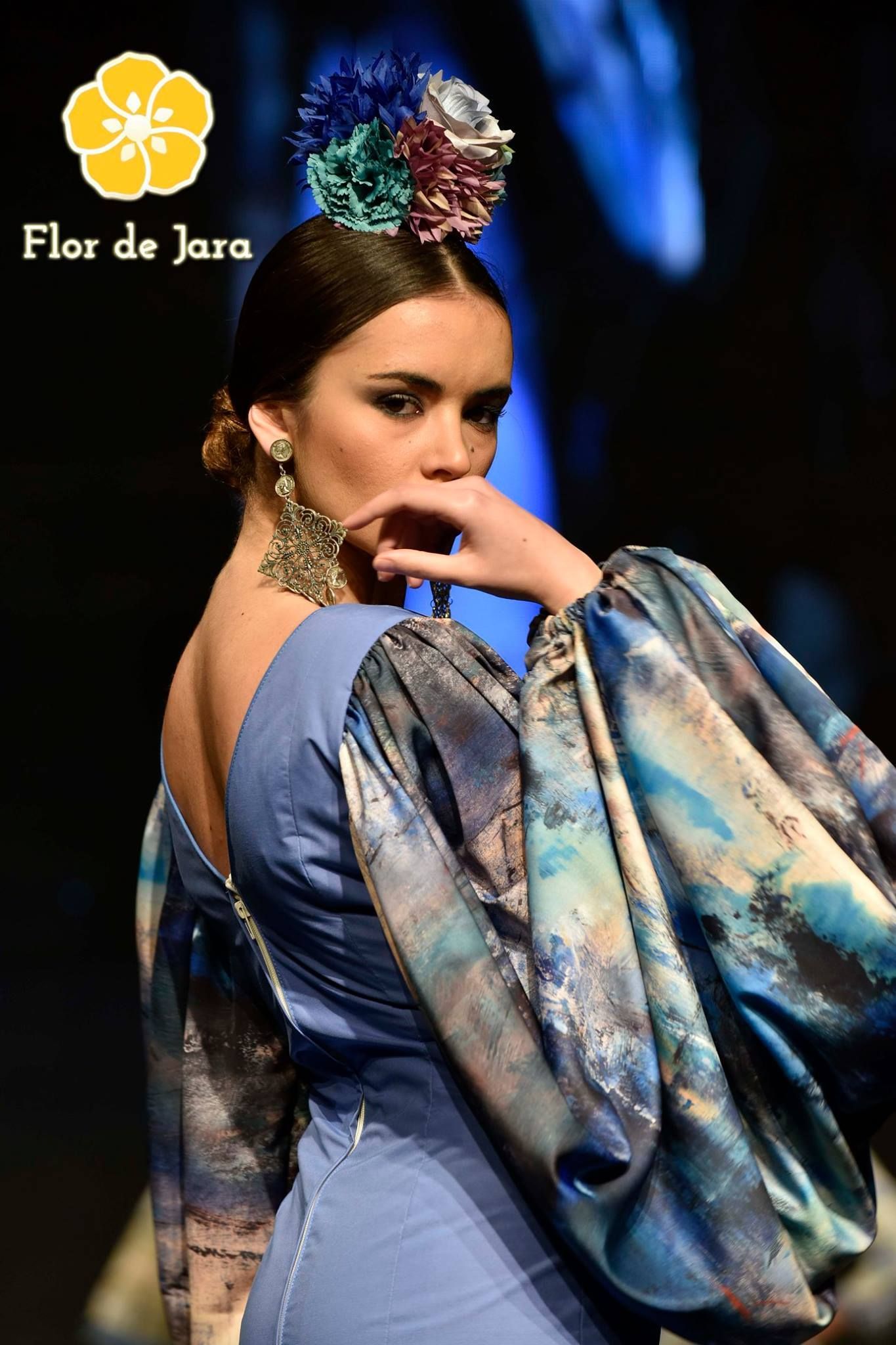 Una mujer que lleva un vestido azul con una flor en el pelo.