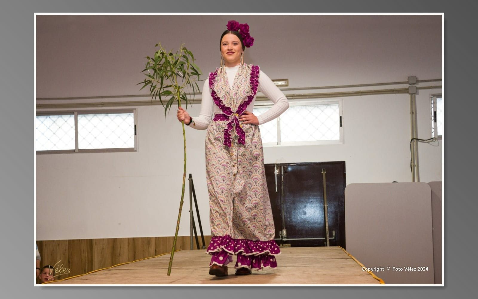 Una mujer con un vestido morado y blanco sostiene una planta.