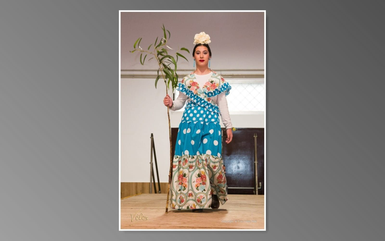 Una mujer con un vestido azul y blanco sostiene una planta.