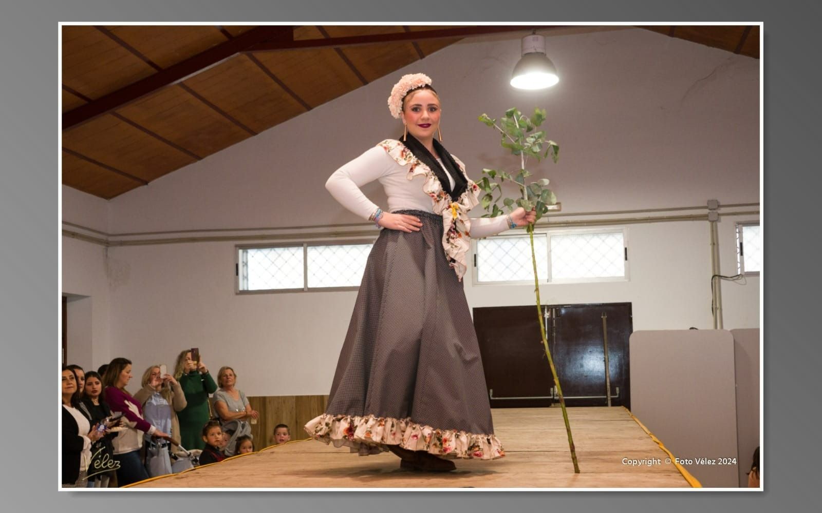 Una mujer está parada en un escenario sosteniendo una planta.
