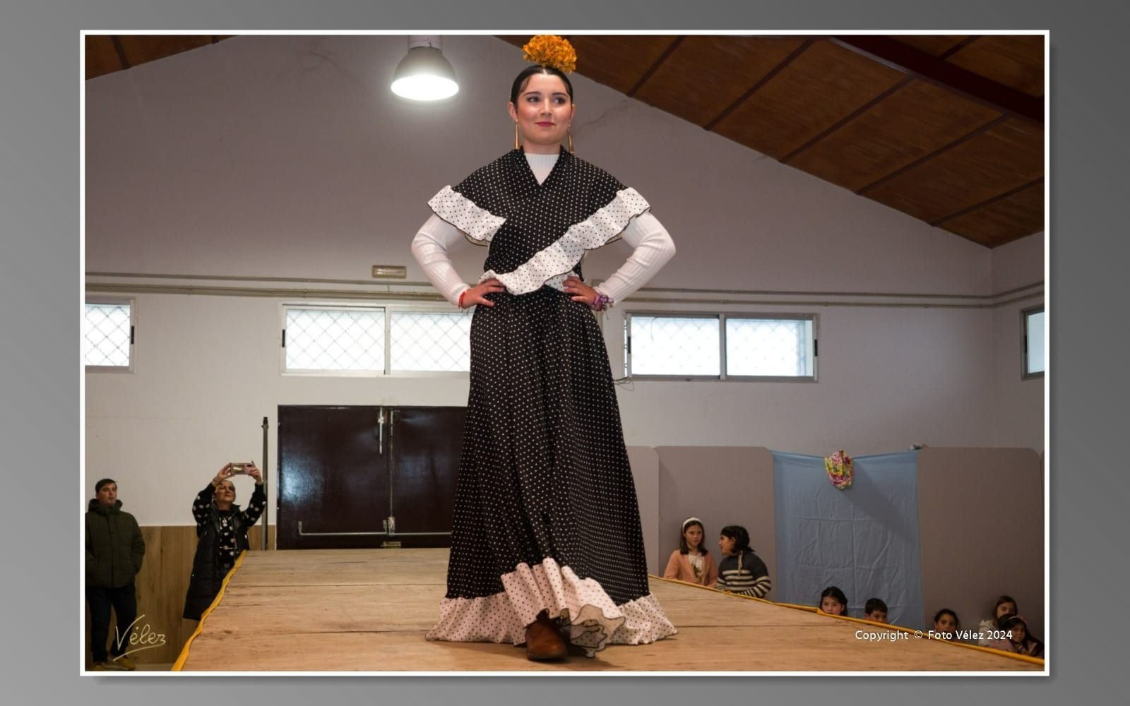 Una mujer con un vestido blanco y negro está de pie en un escenario.