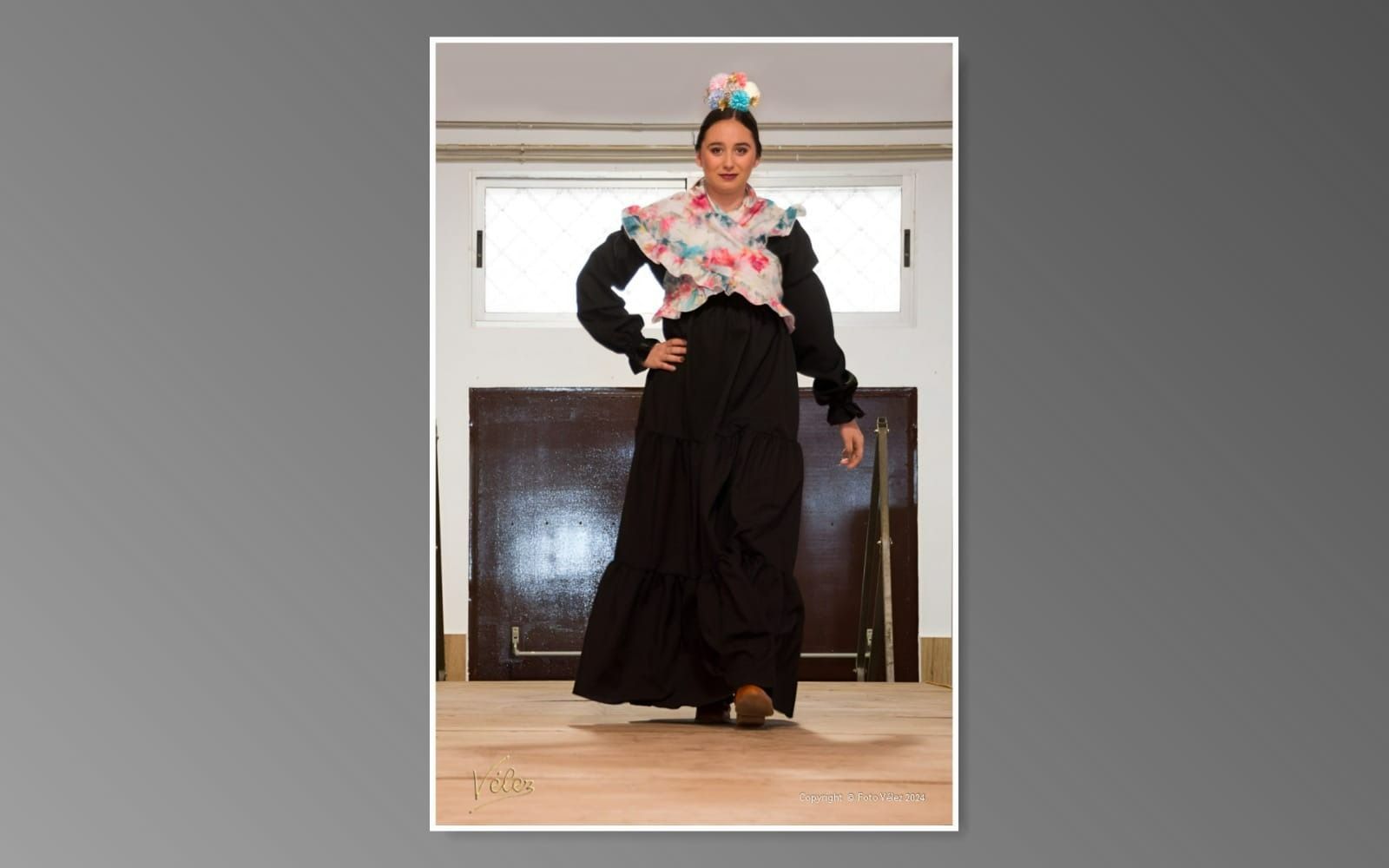 Una mujer con un vestido negro está parada frente a una ventana.