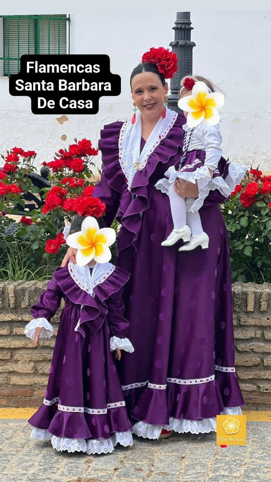 Una mujer con un vestido morado sostiene un niño en sus brazos.