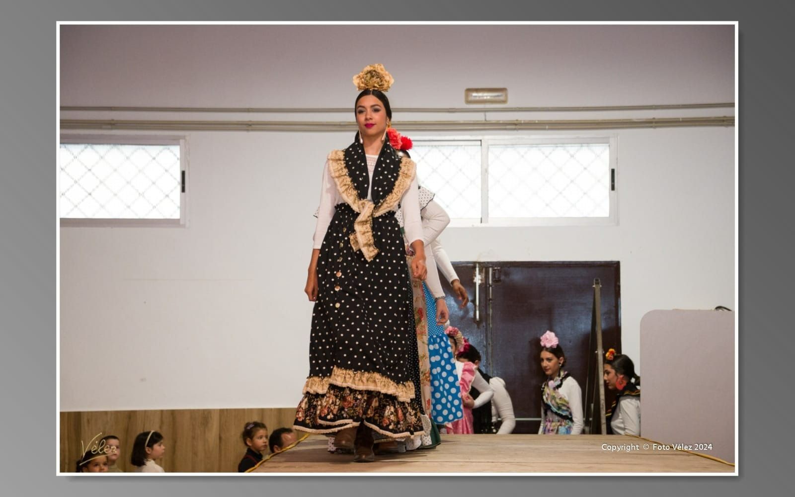 Una mujer con un vestido negro y dorado está parada en un escenario.