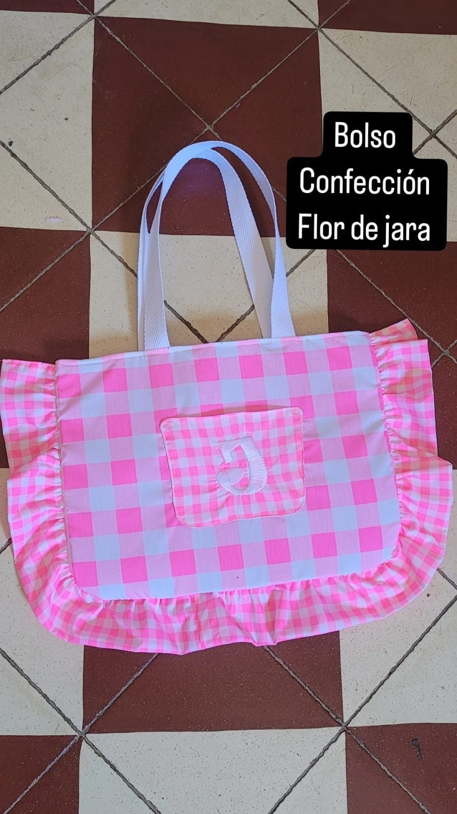 Un bolso tote a cuadros rosa y blanco con volantes