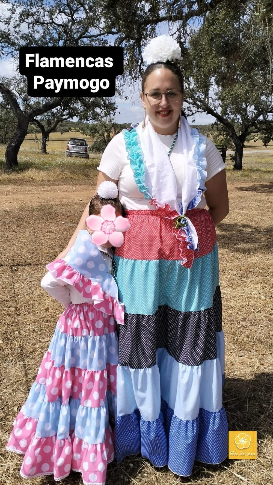 Una mujer con un vestido colorido sostiene una muñeca en un campo.