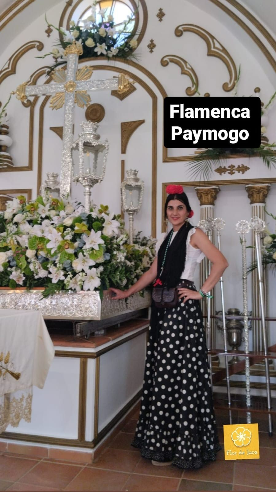 Una mujer con una falda blanca y negra está parada frente a una cruz en una iglesia.