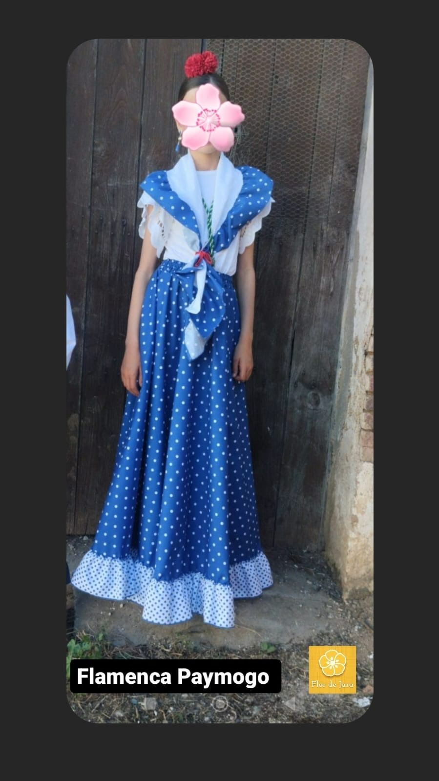 Una mujer con un vestido de lunares azules y blancos está parada frente a una pared de madera.