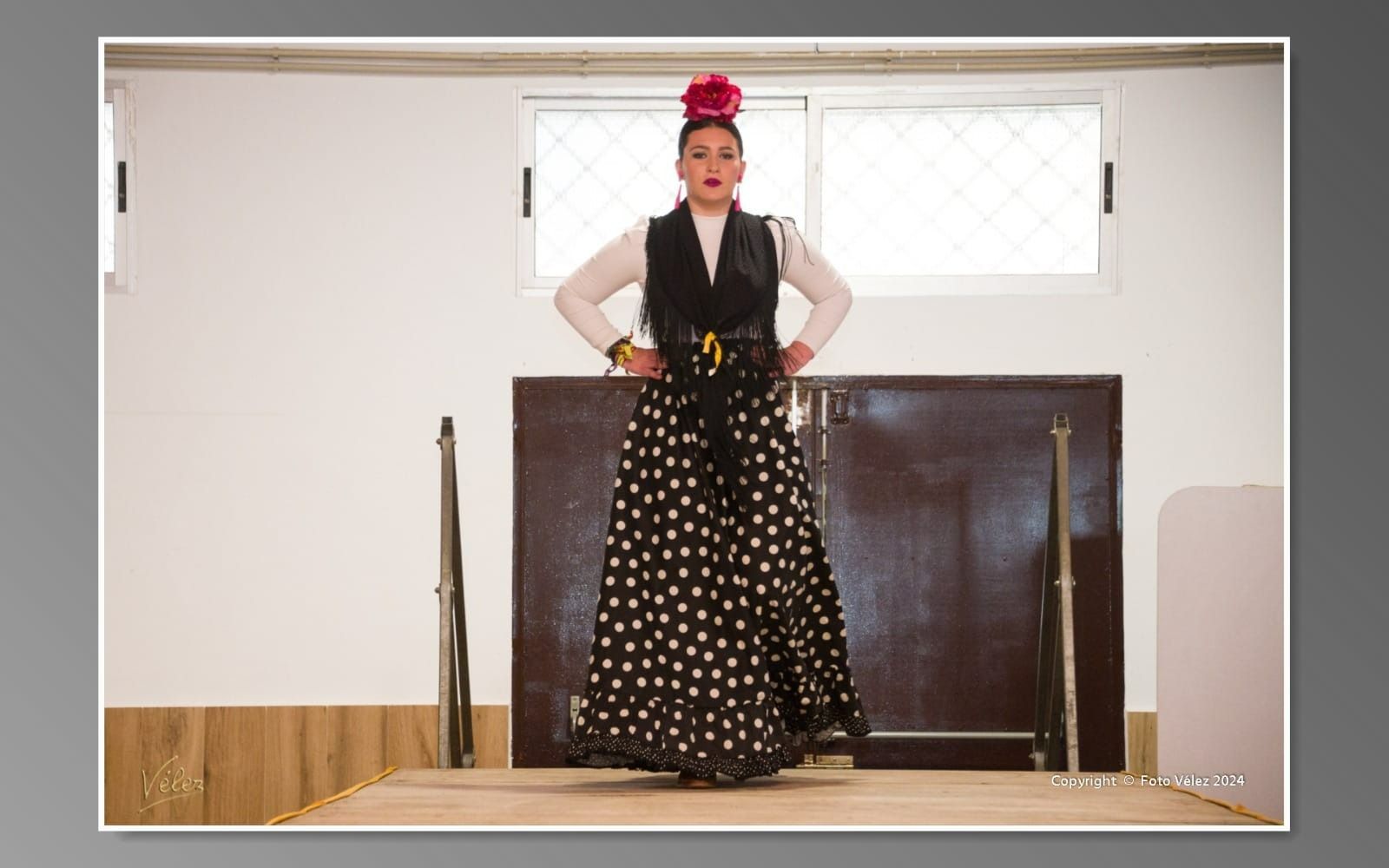 Una mujer con un vestido de lunares blancos y negros está de pie en un escenario.