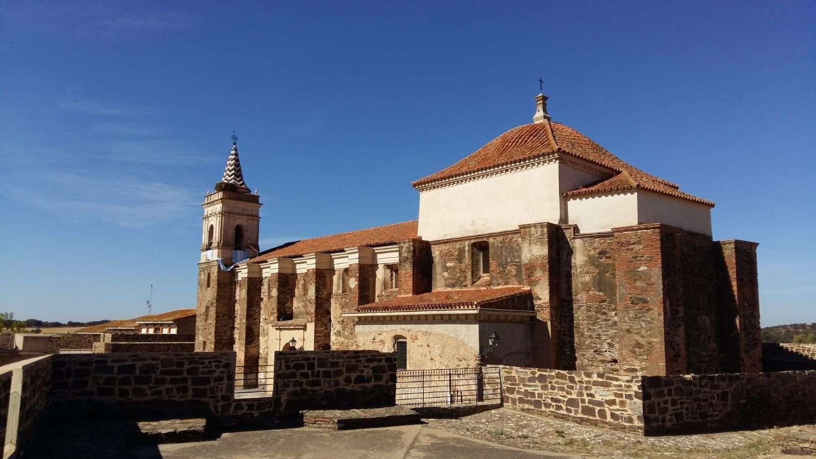 Una iglesia con techo de tejas rojas y un campanario