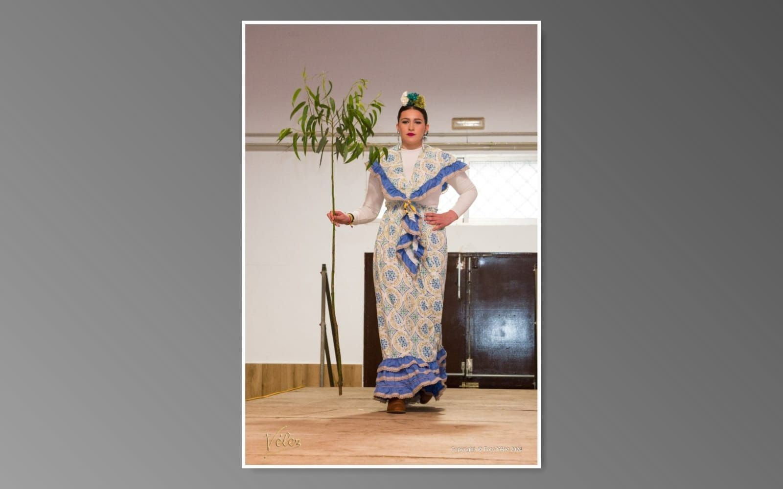 Una mujer con un vestido azul y blanco sostiene una planta.