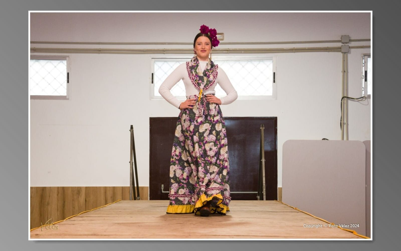 Una mujer con un vestido floral está de pie en un escenario.