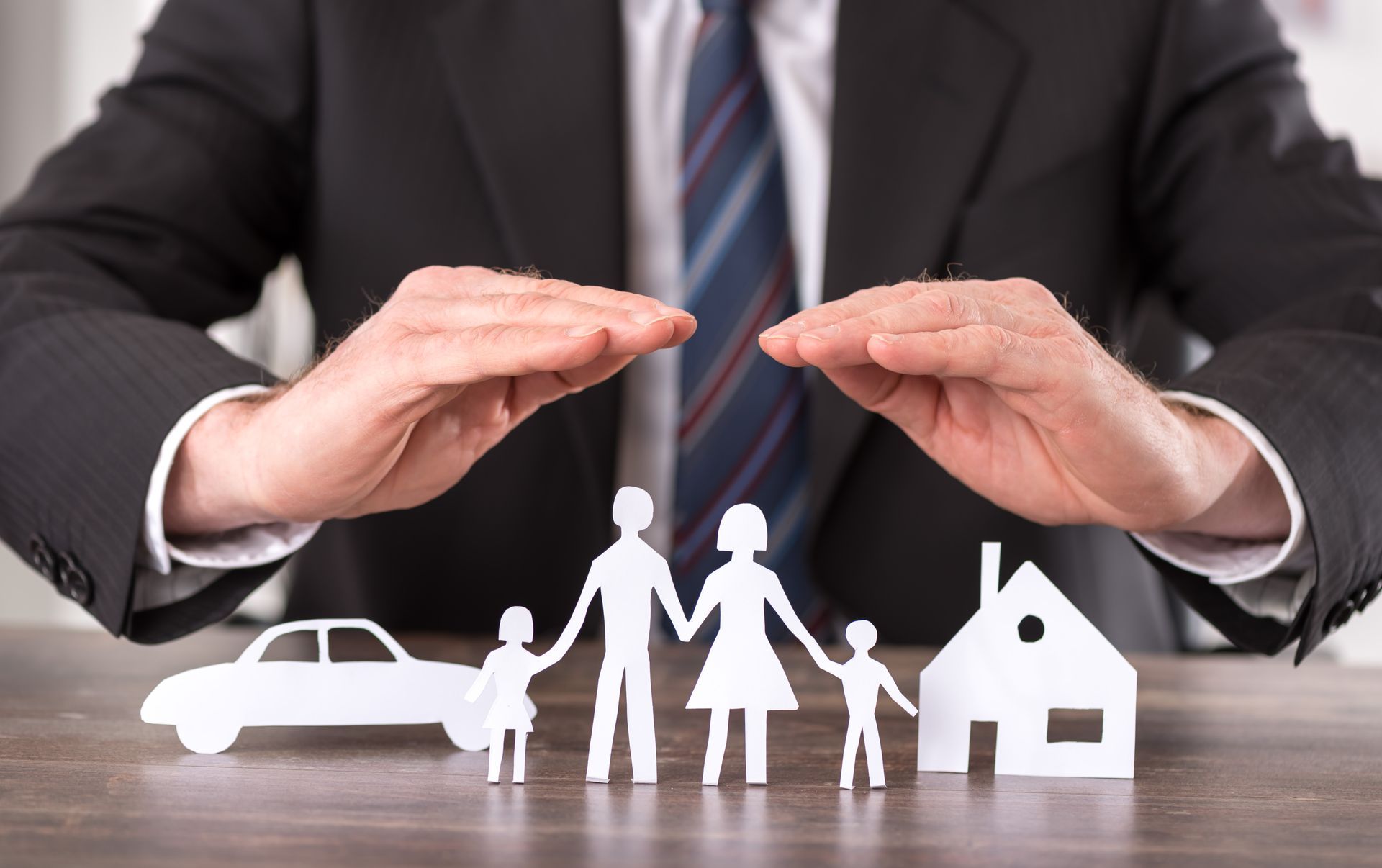 Homme protégeant avec ses mains des icônes de famille, de voiture et de maison.