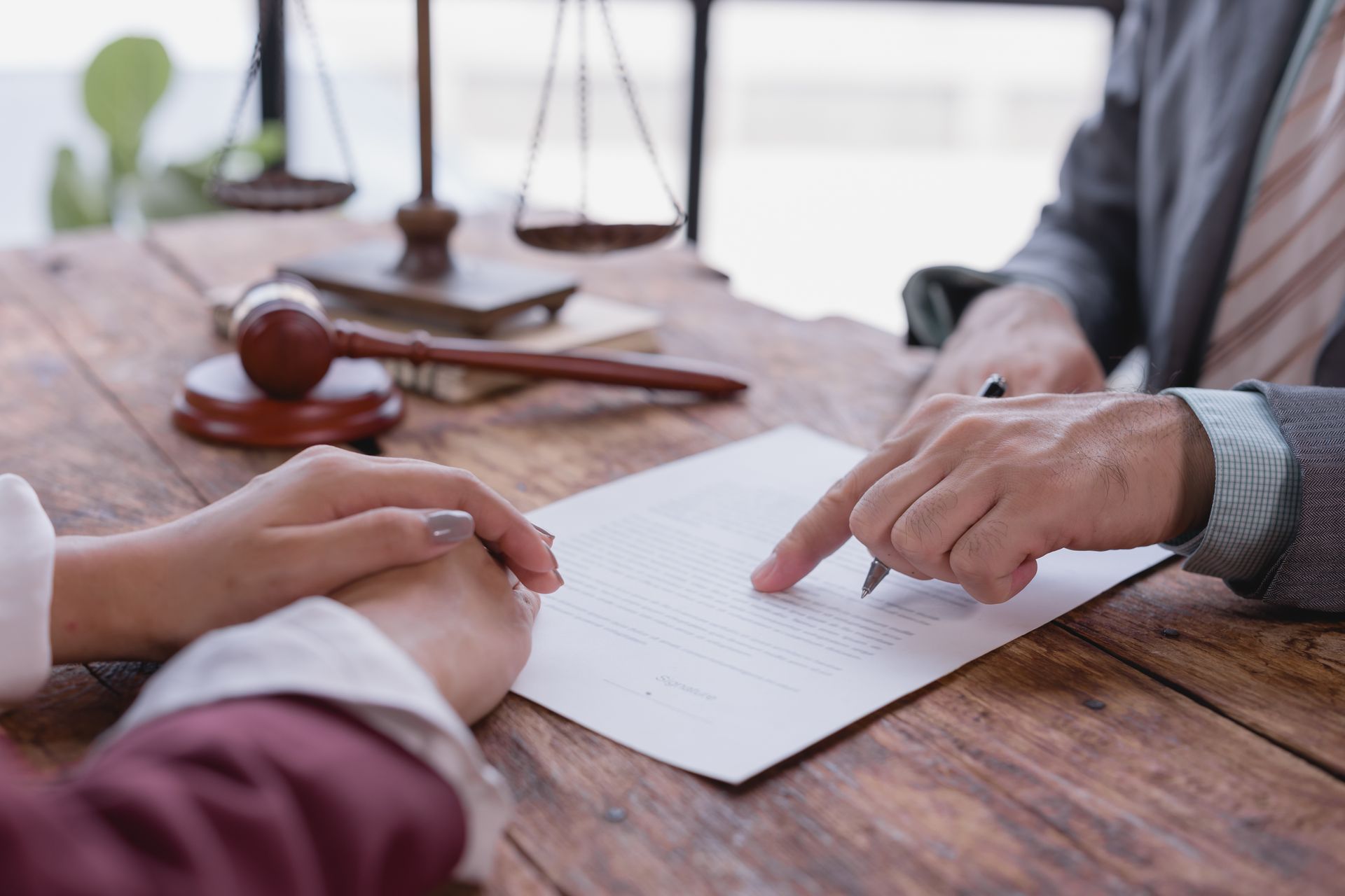 Deux personnes examinent un document sur une table en bois, avec à proximité un maillet et une balance de justice.