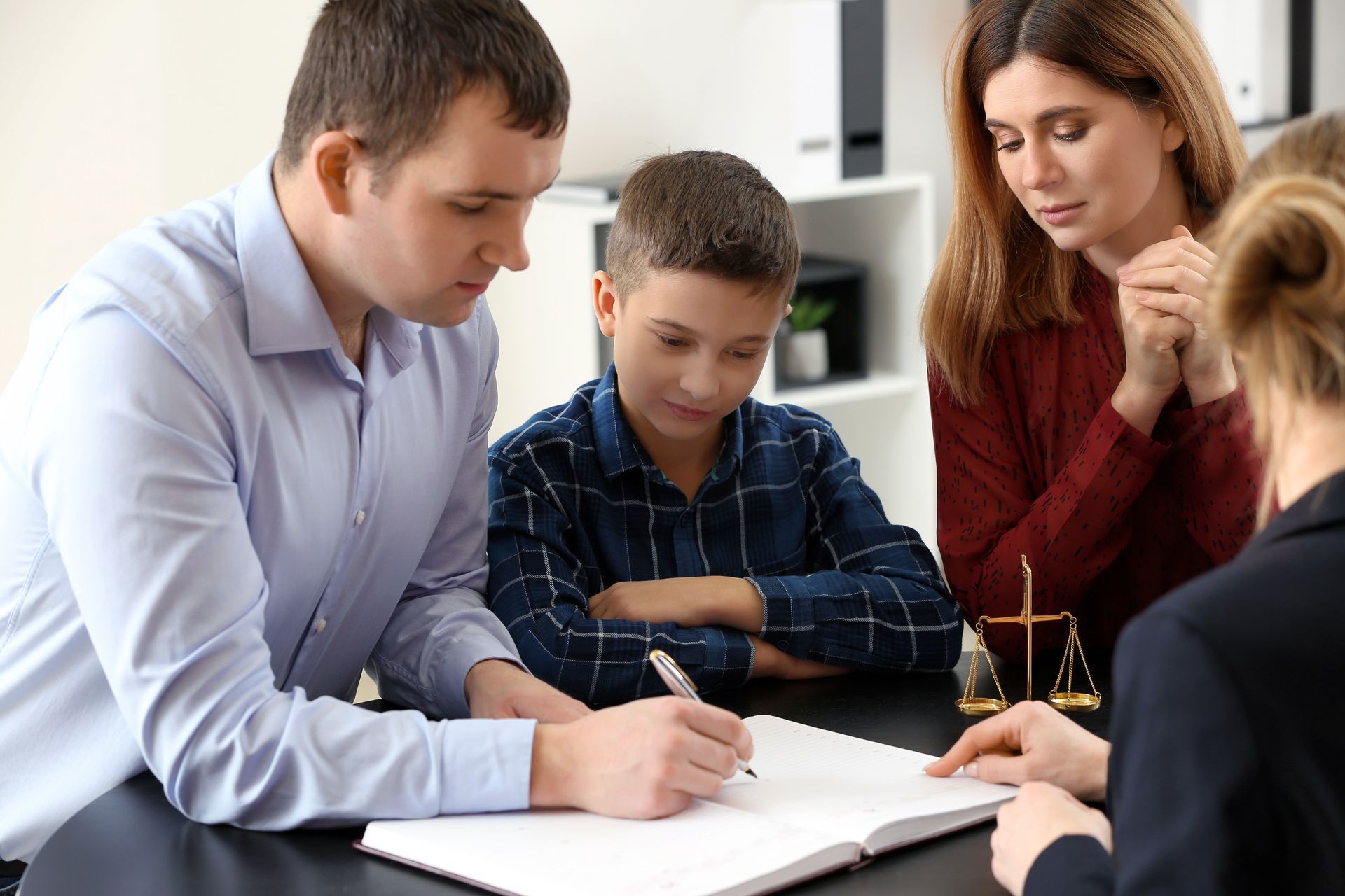 Trois personnes examinent des documents ensemble à une table dans un bureau lumineux.