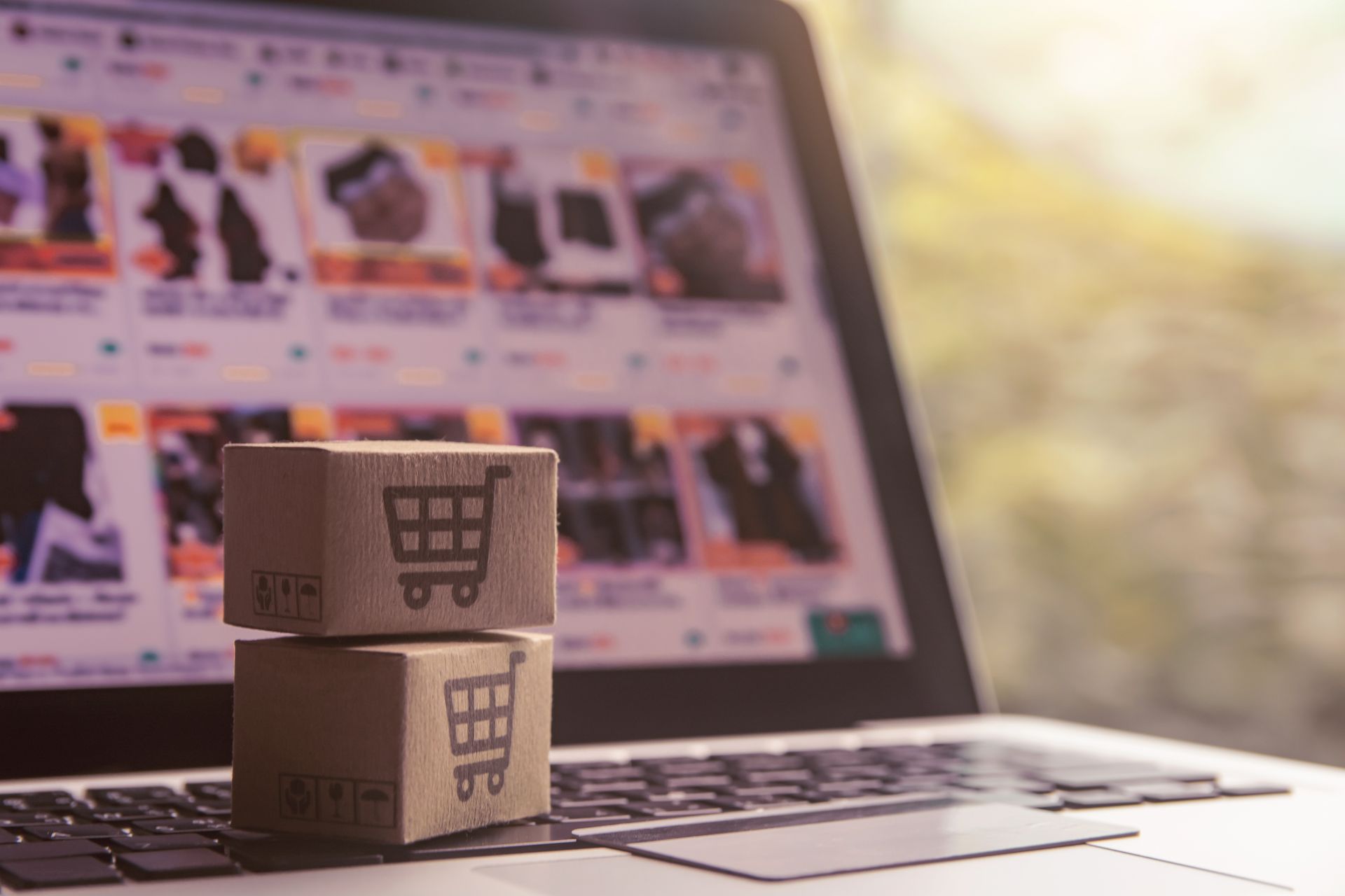 Deux petits cartons ornés d'icônes de panier d'achat sont posés sur un clavier d'ordinateur.
