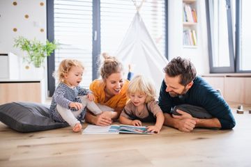 Une famille allongée dans un salon lumineux, partageant un moment de lecture autour d'un livre.
