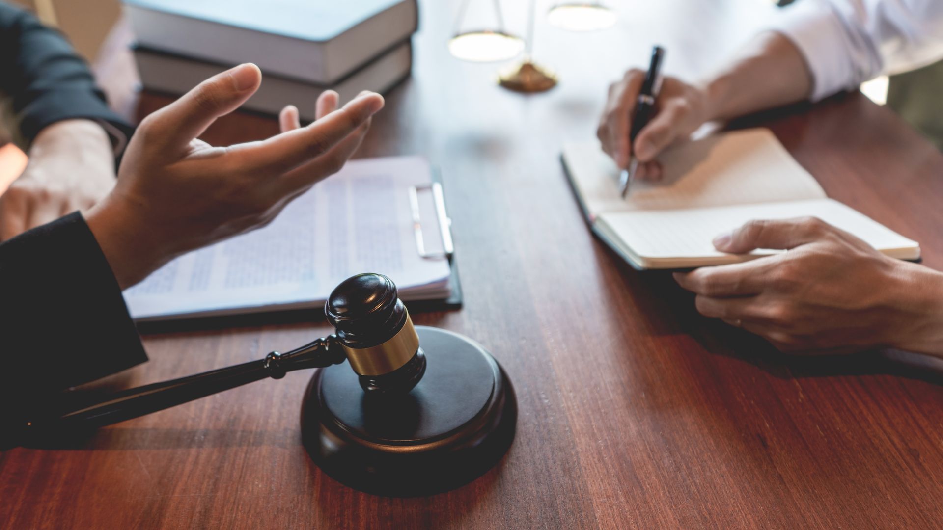 Des avocats se réunissent autour d'une table avec un maillet de juge, des documents et des carnets. 