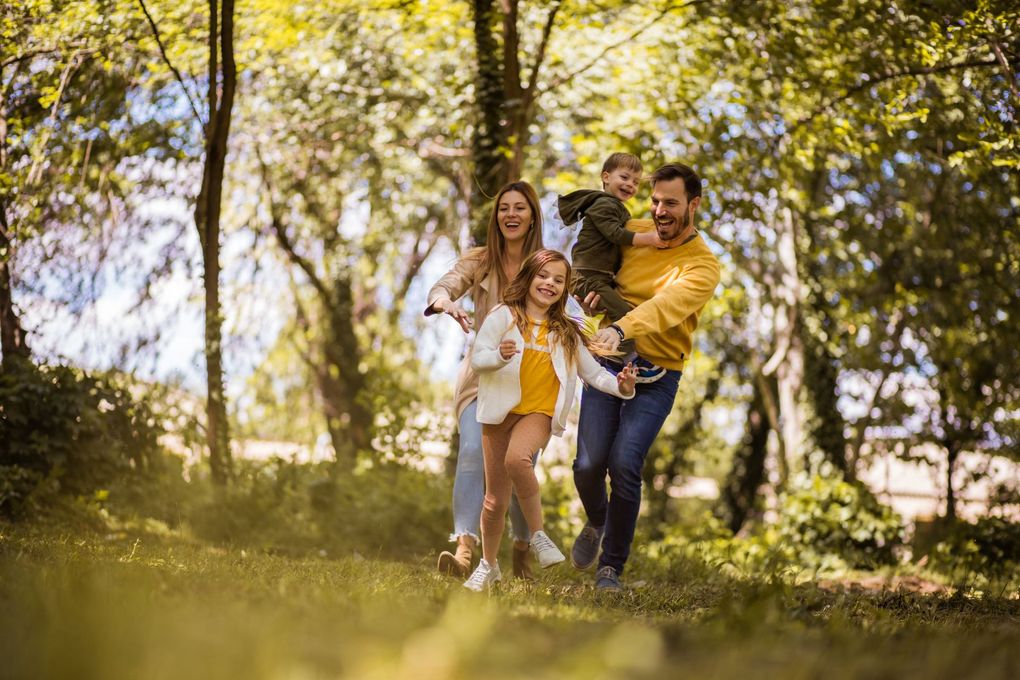 Une famille souriante se promène dans un parc ensoleillé.