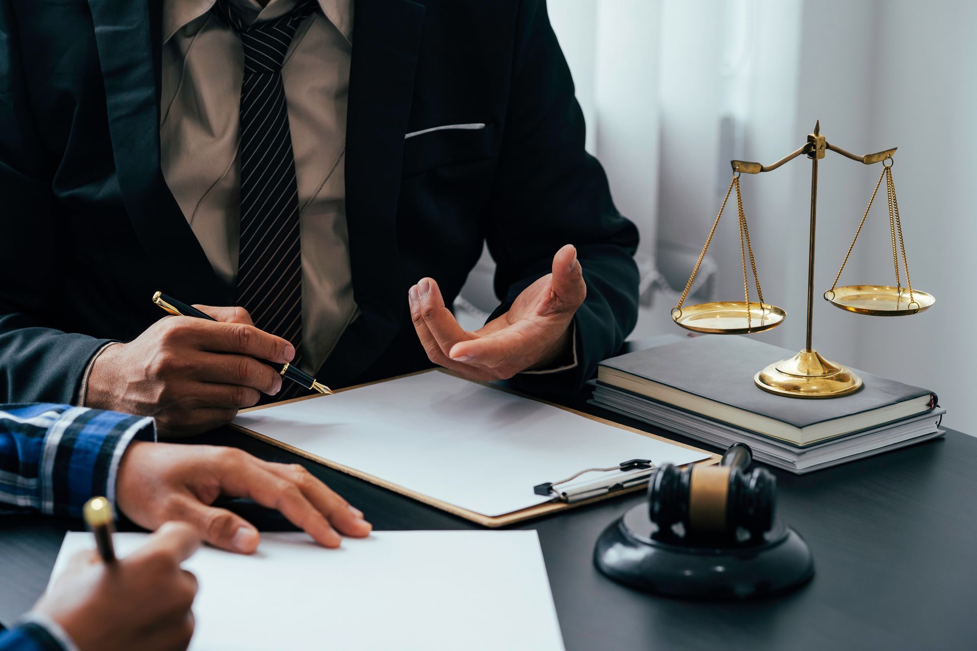 Des avocats discutent d'une affaire à un bureau où se trouvent une balance de justice et un marteau.