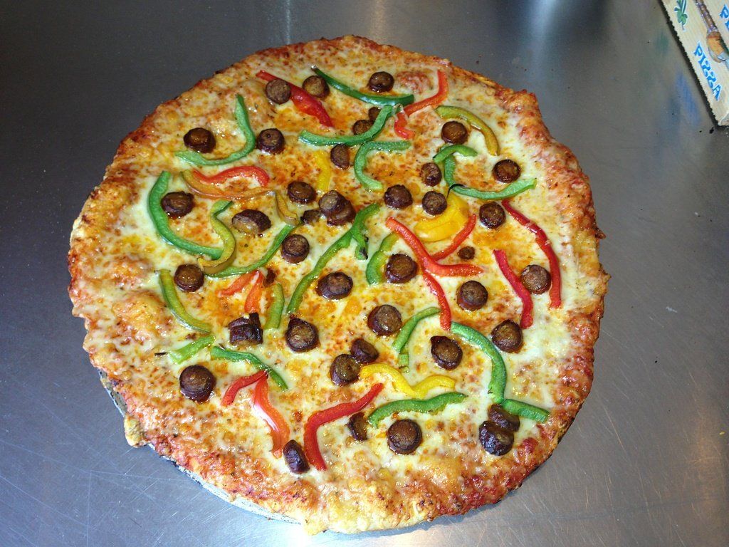 Pizza base crème fraîche avec des poivrons rouges et verts et des olives