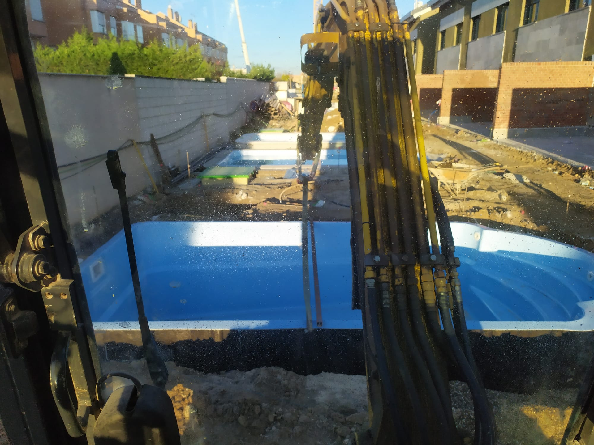 Vista del excavador de la construcción de la piscina: piscinas azules, sitio de construcción, luz solar.