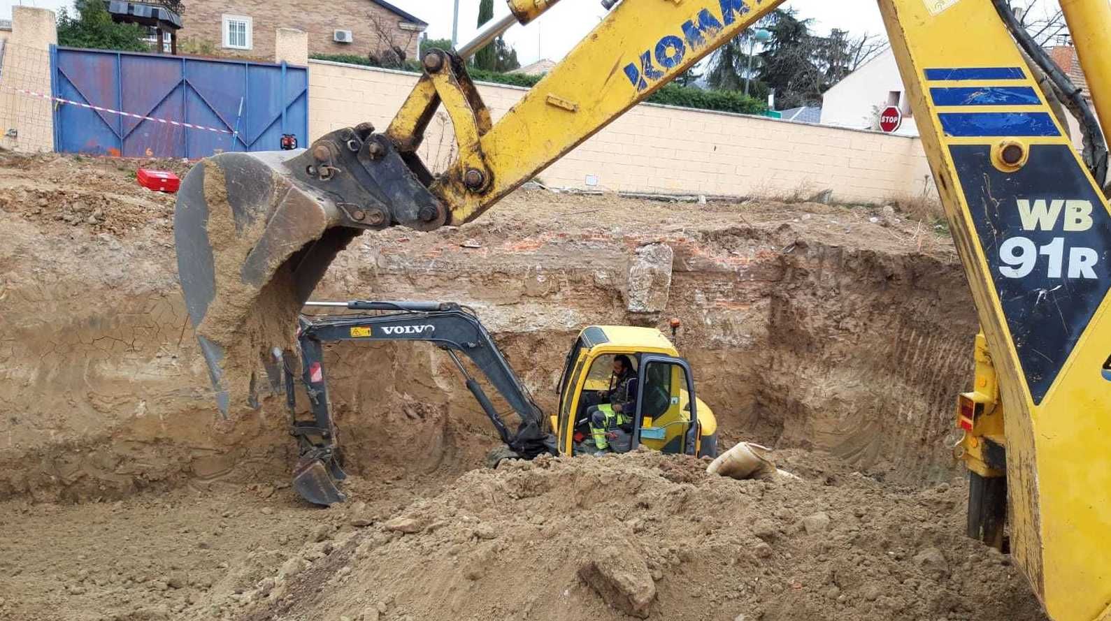 Excavadora amarilla cavando en un pozo de tierra, otra excavadora cerca.