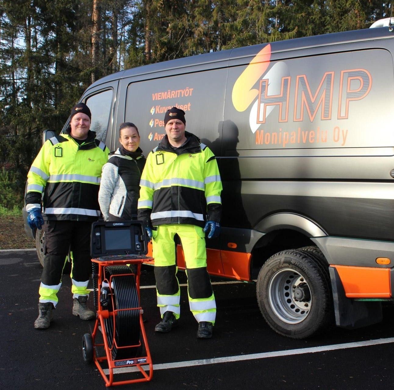 Kolme työpukuihin pukeutunutta ihmistä seisoo HMP Monipalvelu Oy:n pakettiauton vieressä, jonka etualalla on putkitarkastuslaitteisto.