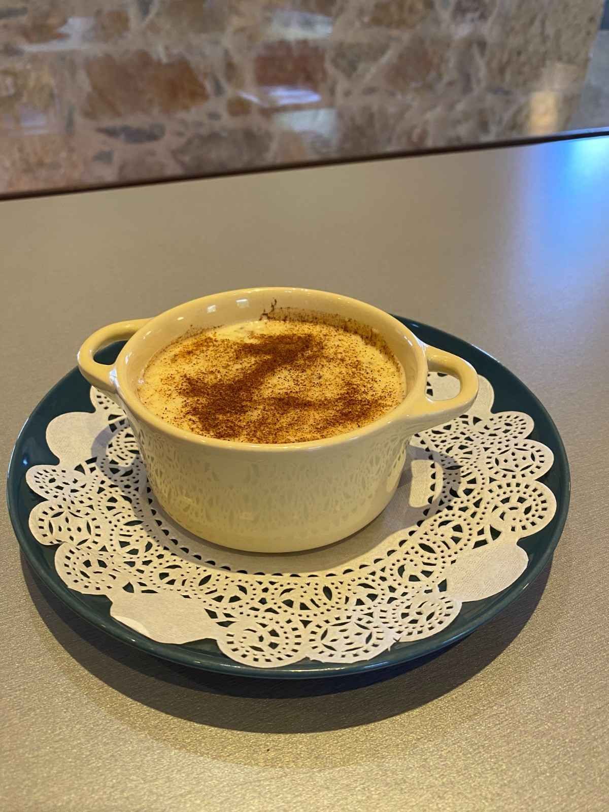 Un postre cremoso espolvoreado con canela, servido en un pequeño plato .