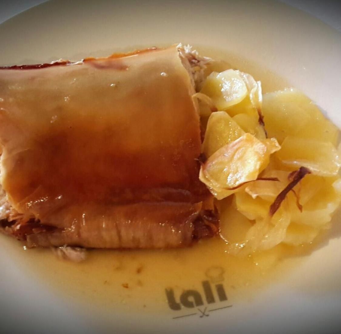 Carne asada servida con patatas en rodajas en una sabrosa salsa en un plato con el logo de la marca.