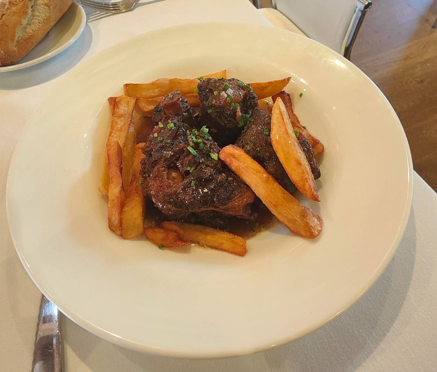 Un plato de trozos de carne estofada servido con patatas fritas gruesas y doradas.