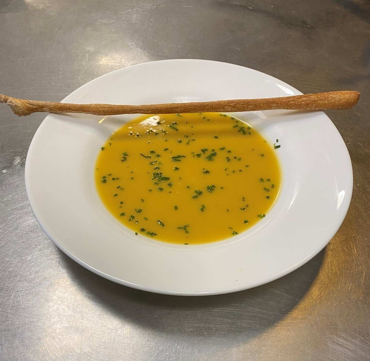 Un tazón de sopa de color amarillo brillante espolvoreada con hierbas frescas .
