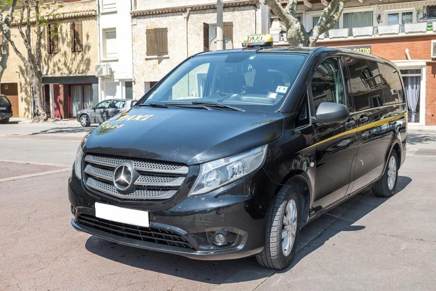 Un taxi Mercedes noir stationné dans une rue ensoleillée.