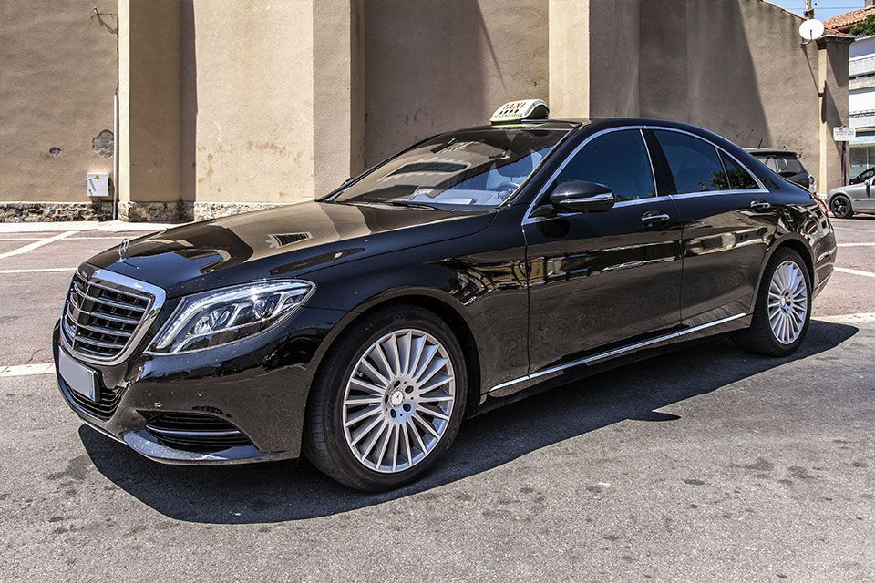 Berline Mercedes noire, taxi avec gyrophare, stationnée dans une rue de la ville.