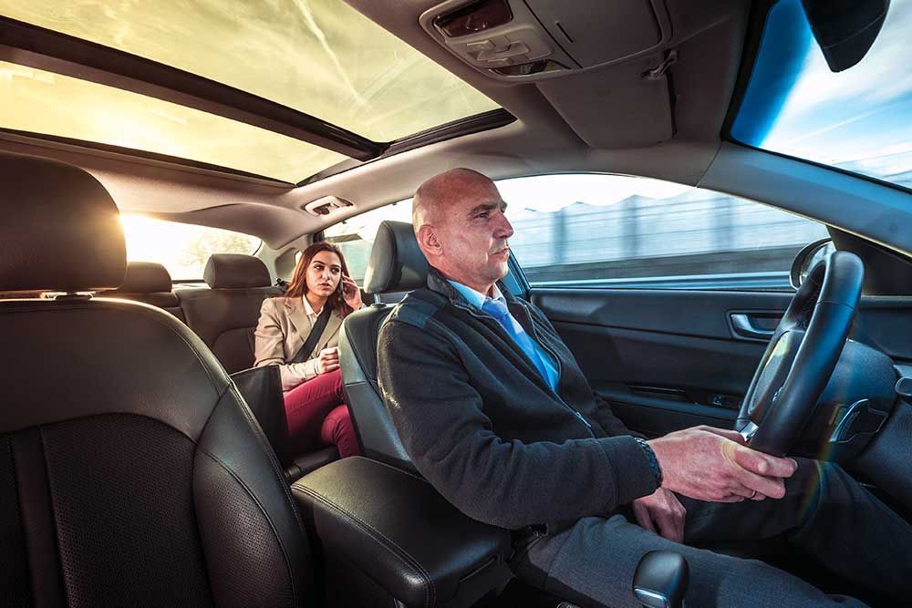 À l'intérieur d'une voiture : conducteur et passager. Une femme au téléphone. Journée ensoleillée à travers le toit ouvrant.