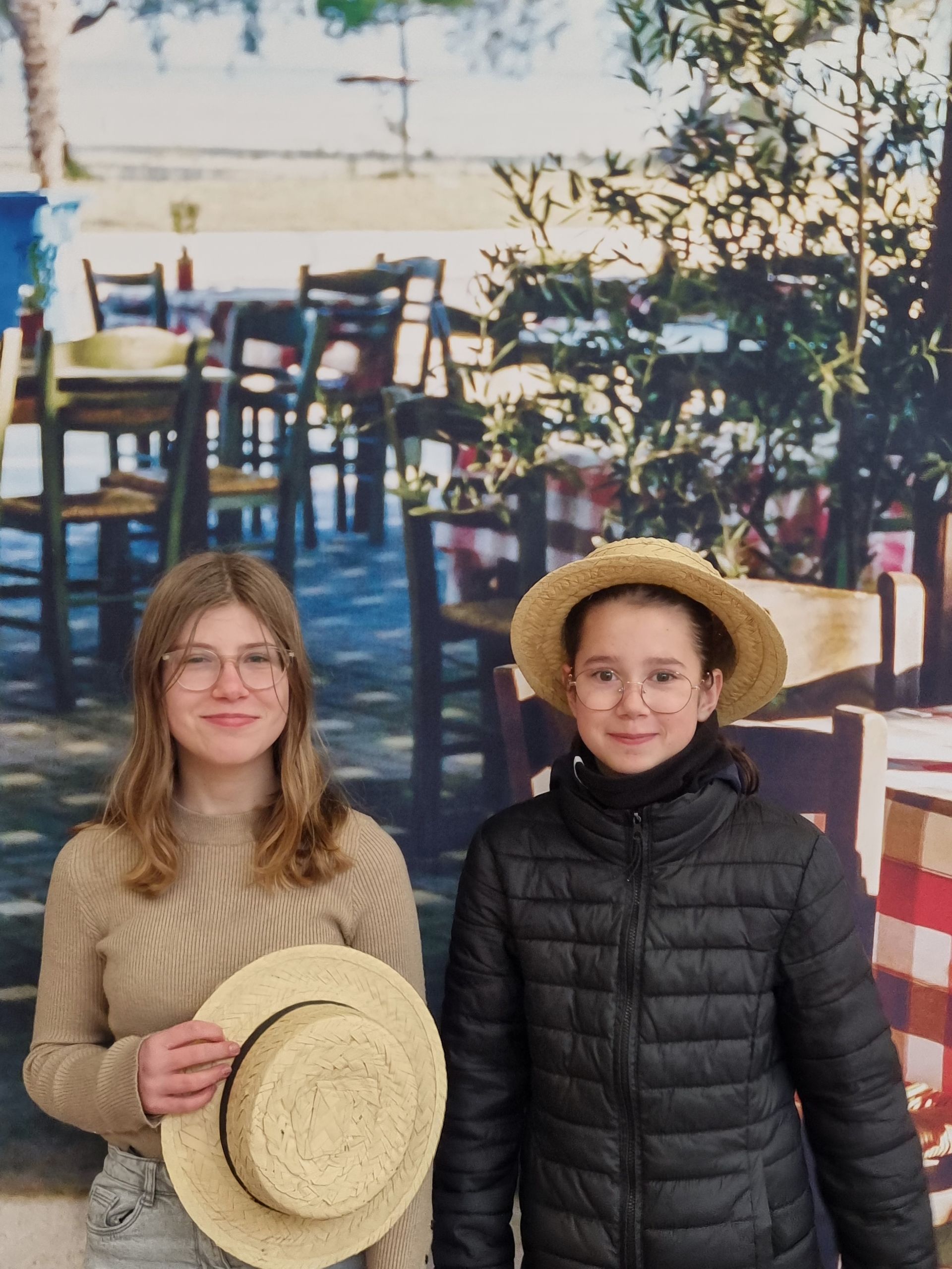 Deux filles qui sourient devant des chaises en bois