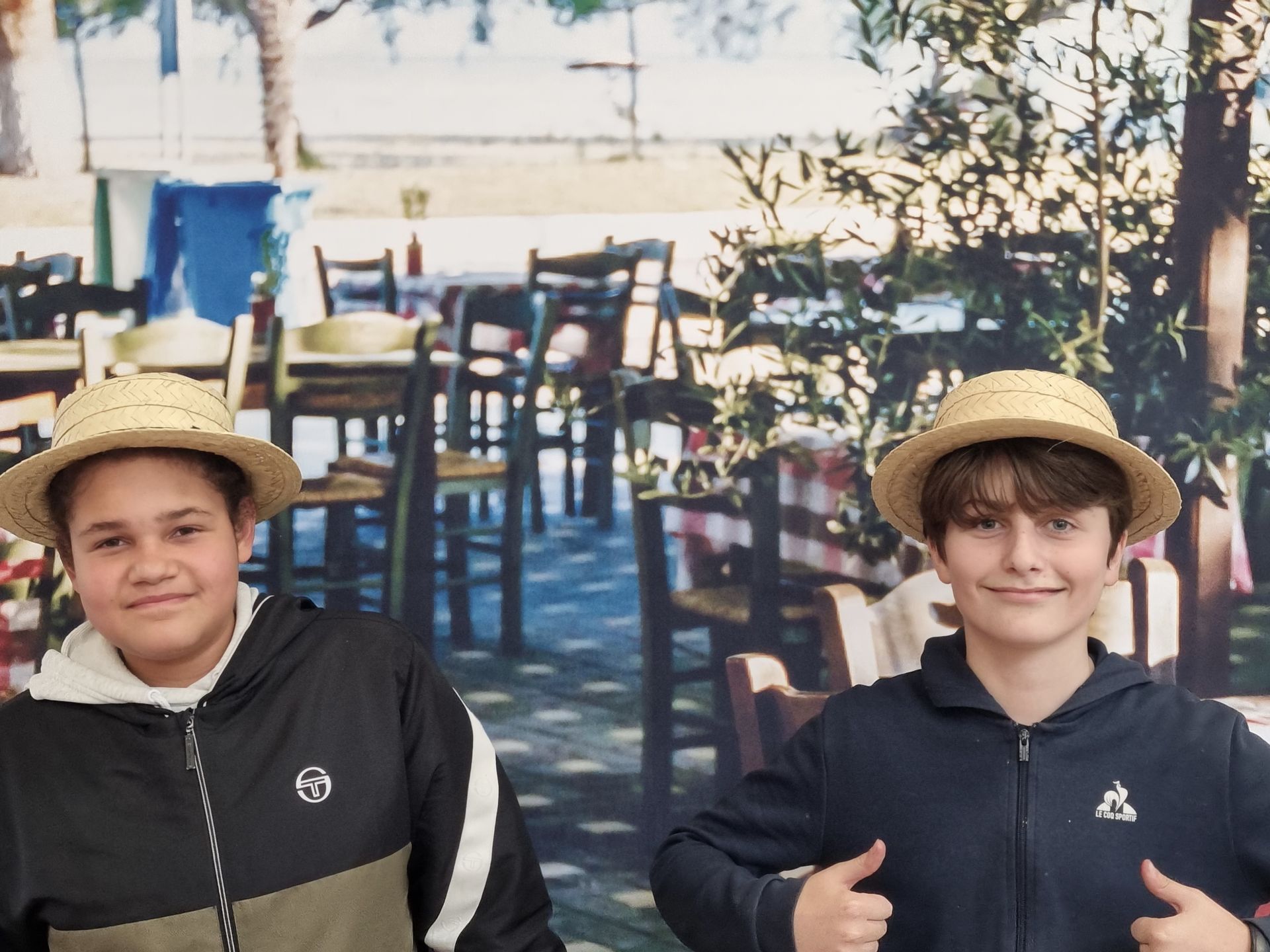 Deux garçons qui sourient devant une affiche avec des tables