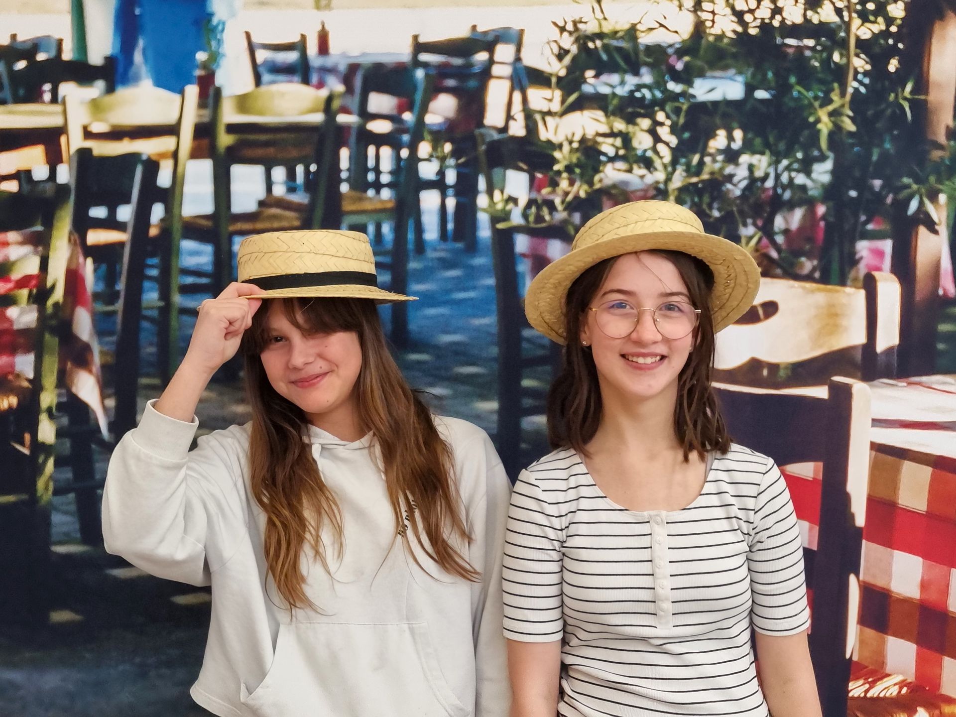 Deux élèves qui portent des chapeaux et font une photo devant des tables