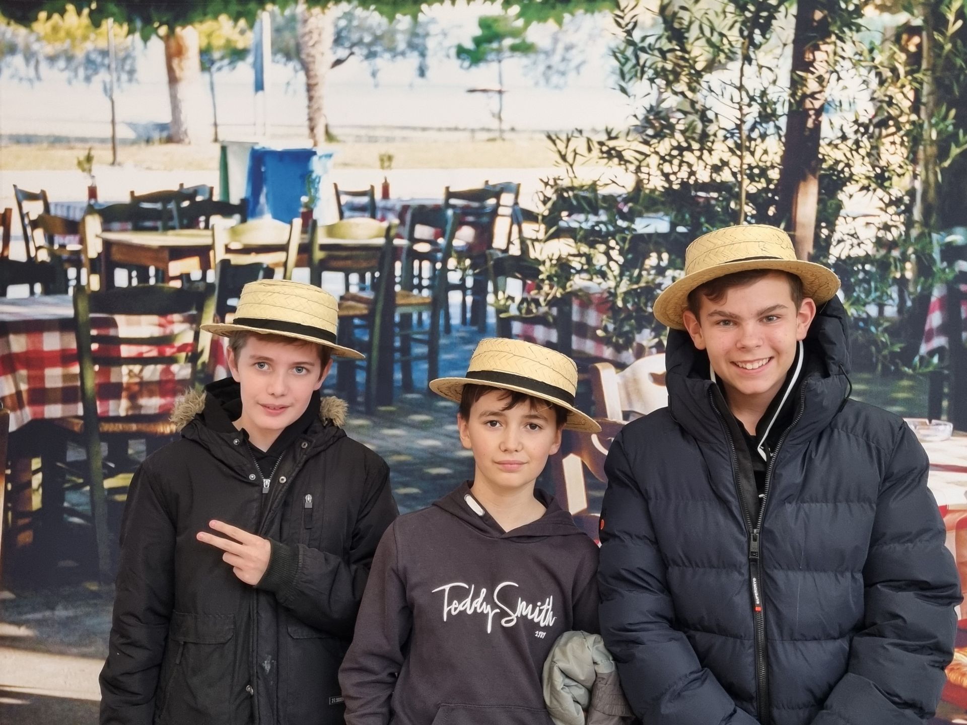 Un groupe de garçons qui prennent la pose devant des tables et des chaises en bois