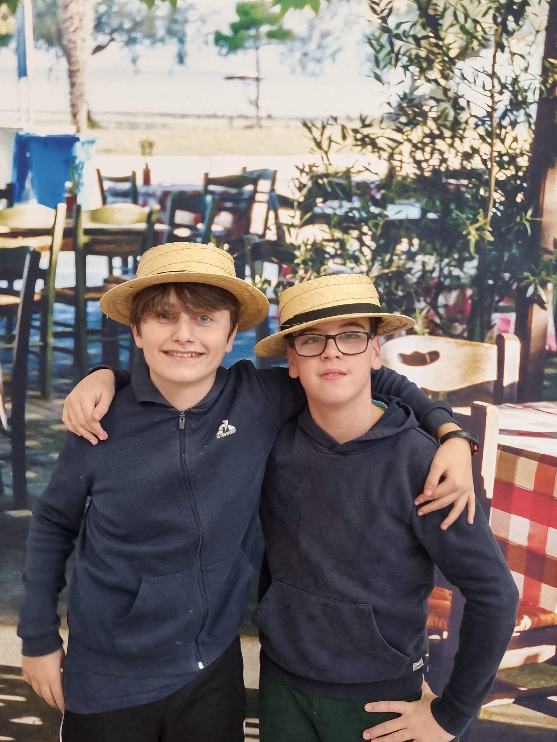 Deux élèves qui sourient pour une photo et qui portent des chapeaux en pailles