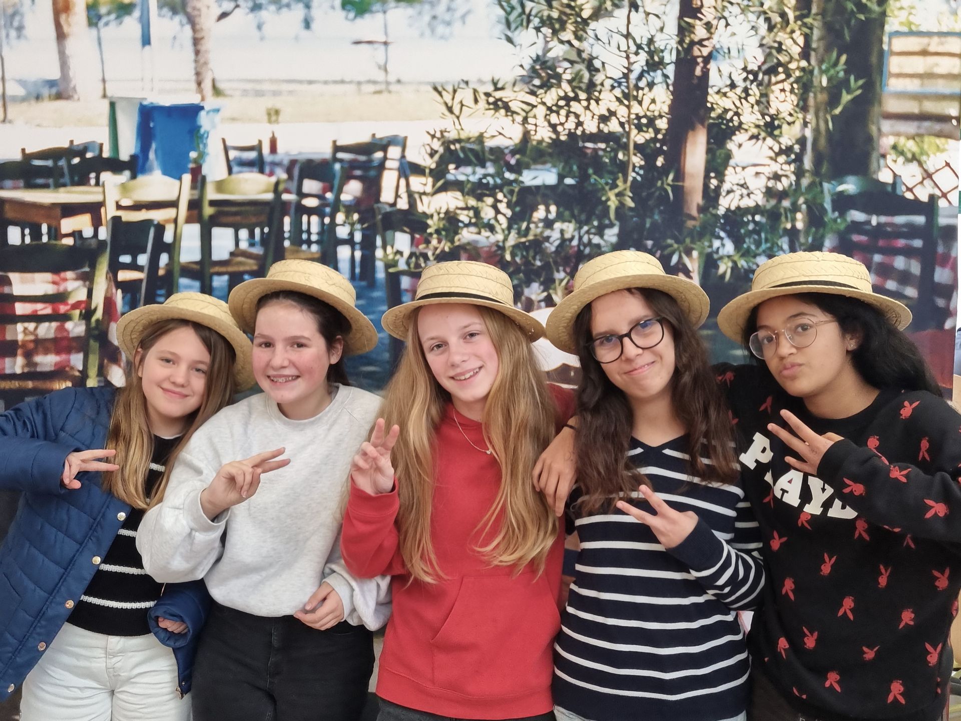 Des collégiennes qui prennent une photo devant une affiche avec des chaises en bois