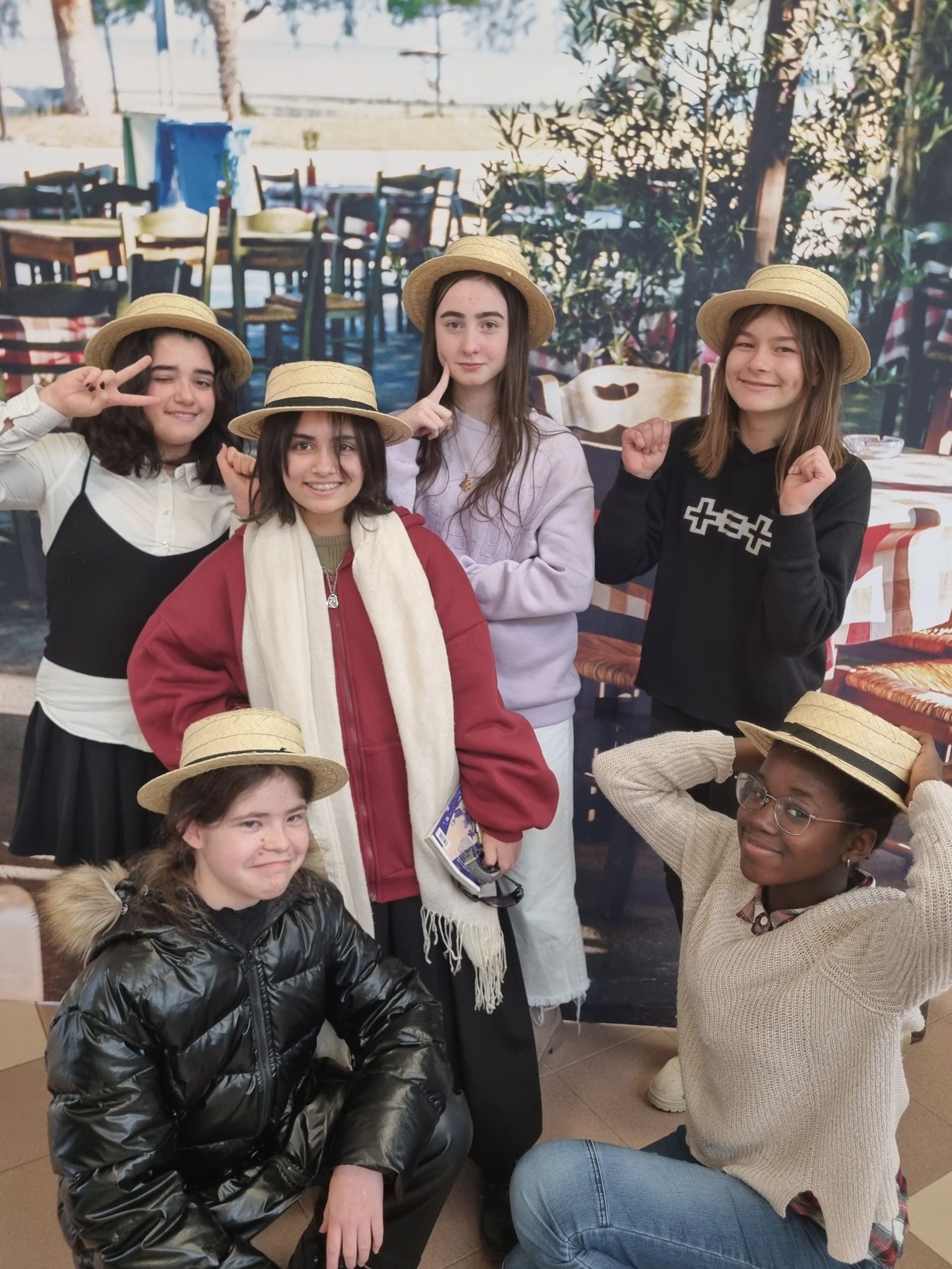 Un groupe de collégiennes qui portent des chapeaux en pailles et prennent la pose