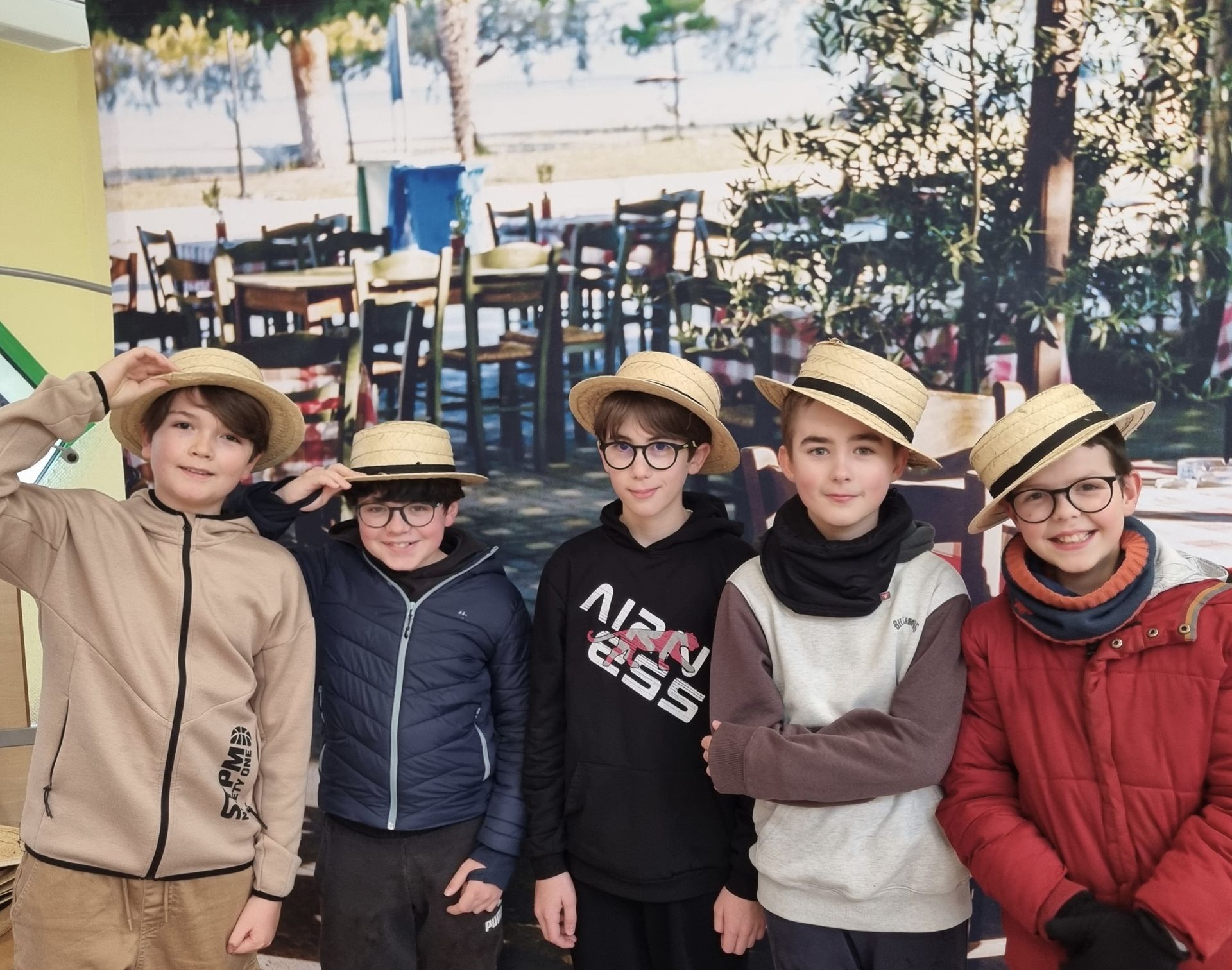 Des collégiens avec des chapeaux en pailles prenant la pose devant une photo avec des tables