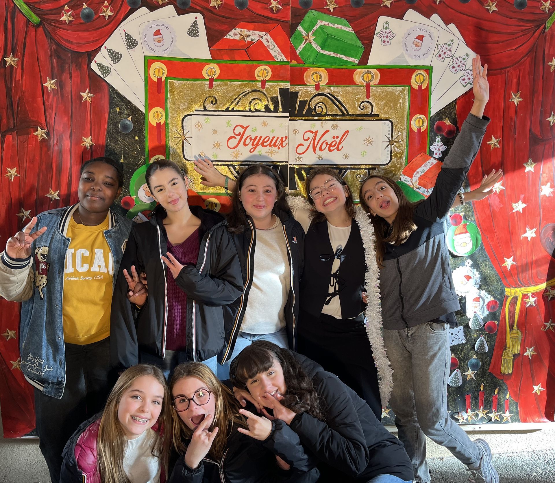 Un groupe d'élève qui sourient et prennent une photo avec un décor pour les fêtes