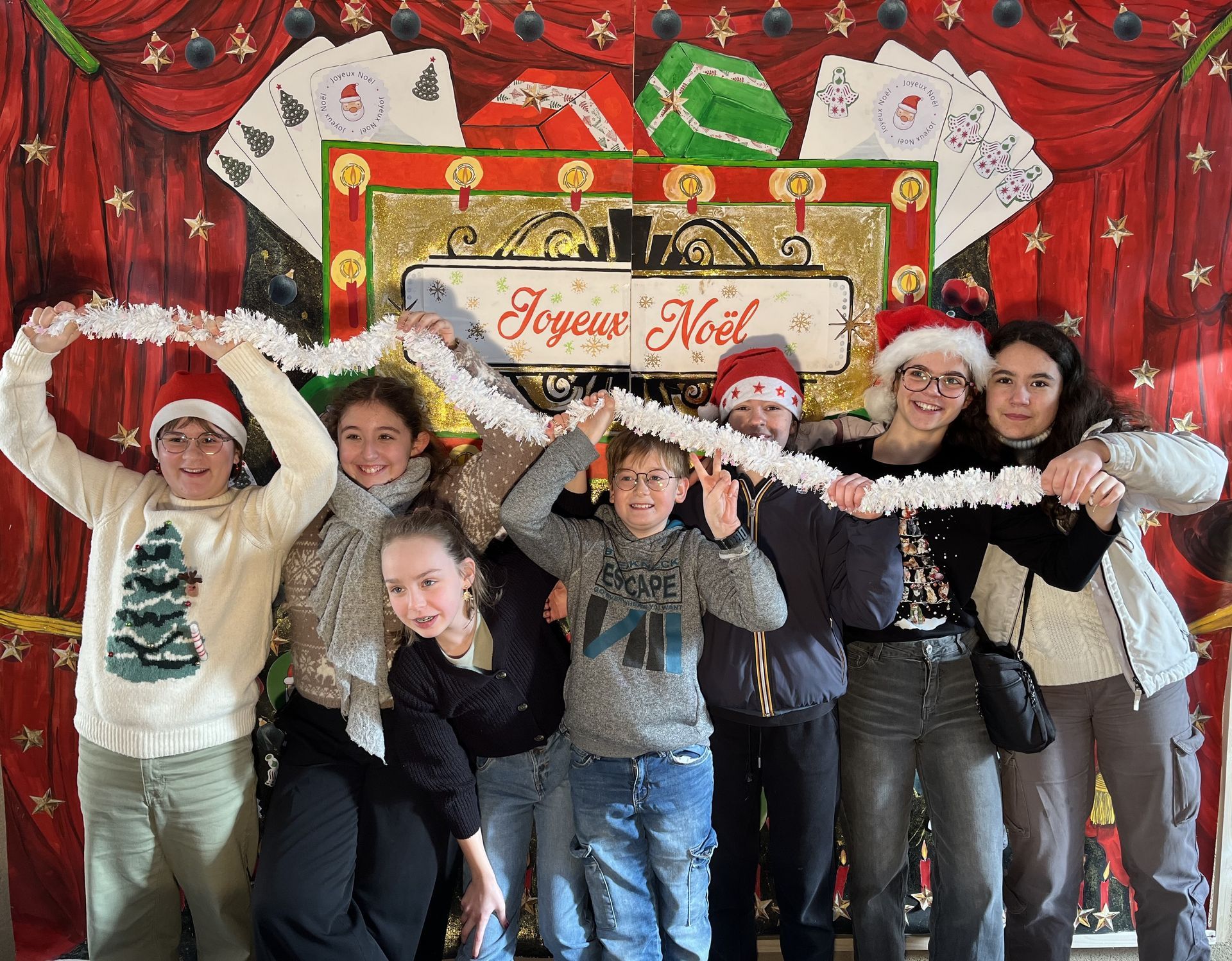 Un groupe de collégiens qui tiennent une guirlande de Noël devant une pancarte de Noël 